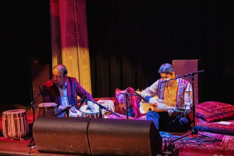 Percussionist Toryalai Hashimi and Rubab player Quraishi are seated on stage during a performance at the Cedar Cultural Center in Minneapolis