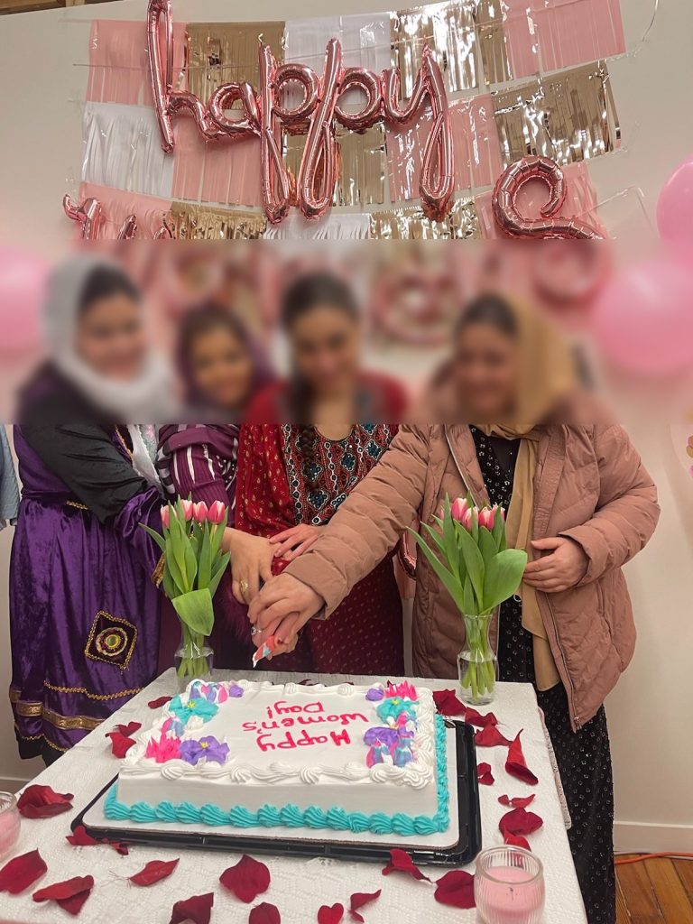 A group of 4 women cut a cake in front of streamers and balloons.